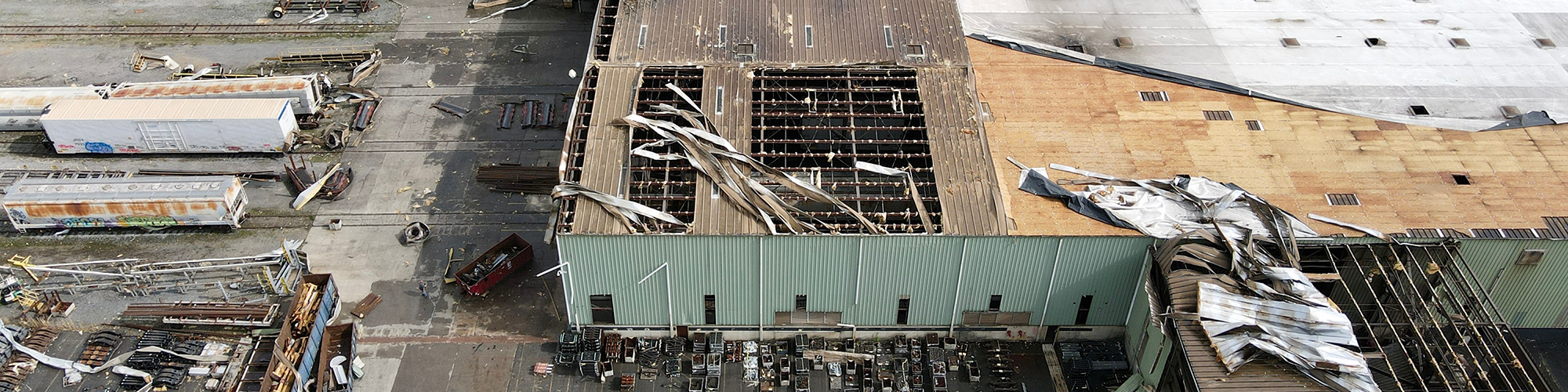 A commercial building with a torn-off roof and debris everywhere in the aftermath of a tornado.